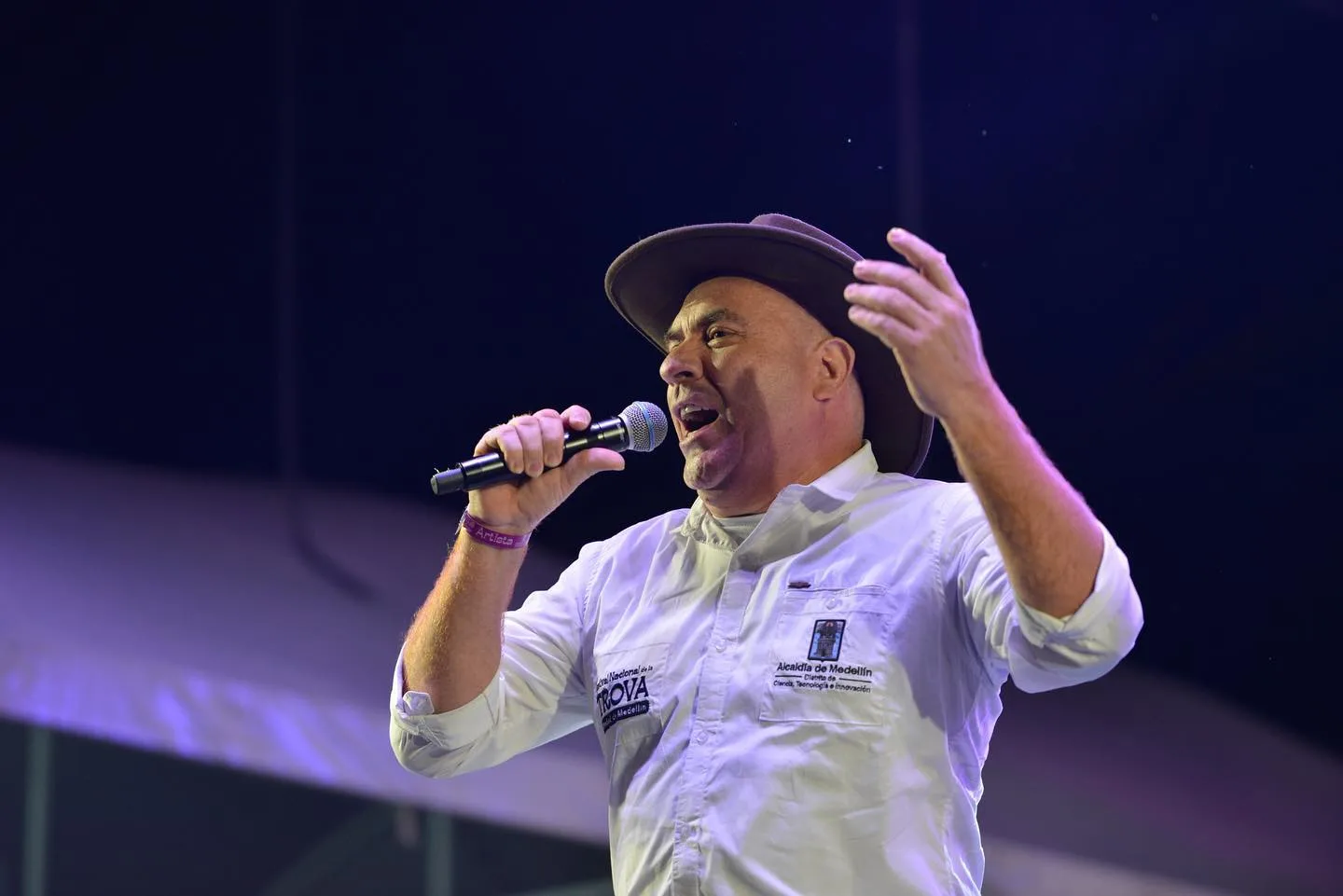 Trovador canta con sombrero bajo luz morada